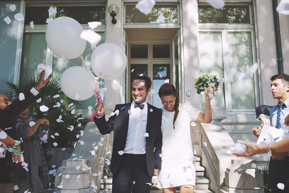 Confetti shot.  Bride wearing Vanessa Bruno and groom holding white balloons.  Two newlyweds looking happy.  Image by Hearts on Fire Photography.