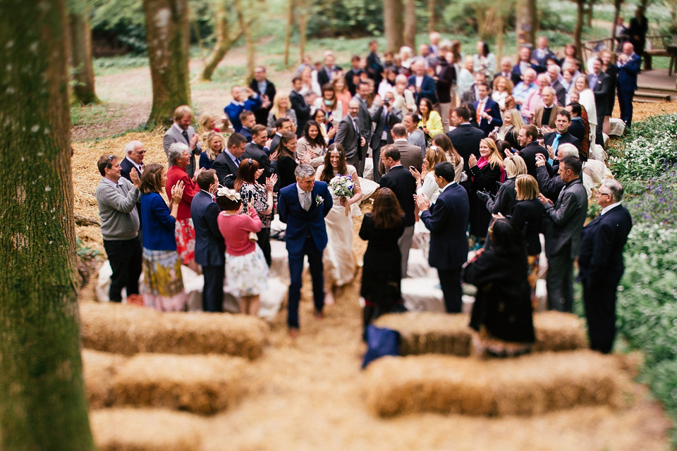 The bride wears a Sabina Motasem gown for her rustic, festival style wedding with glamping near the forrest. Photography by Joanna Nicole.