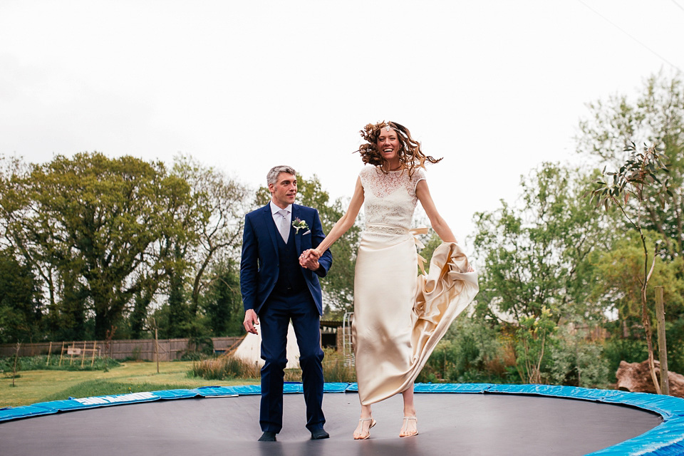 The bride wears a Sabina Motasem gown for her rustic, festival style wedding with glamping near the forrest. Photography by Joanna Nicole.