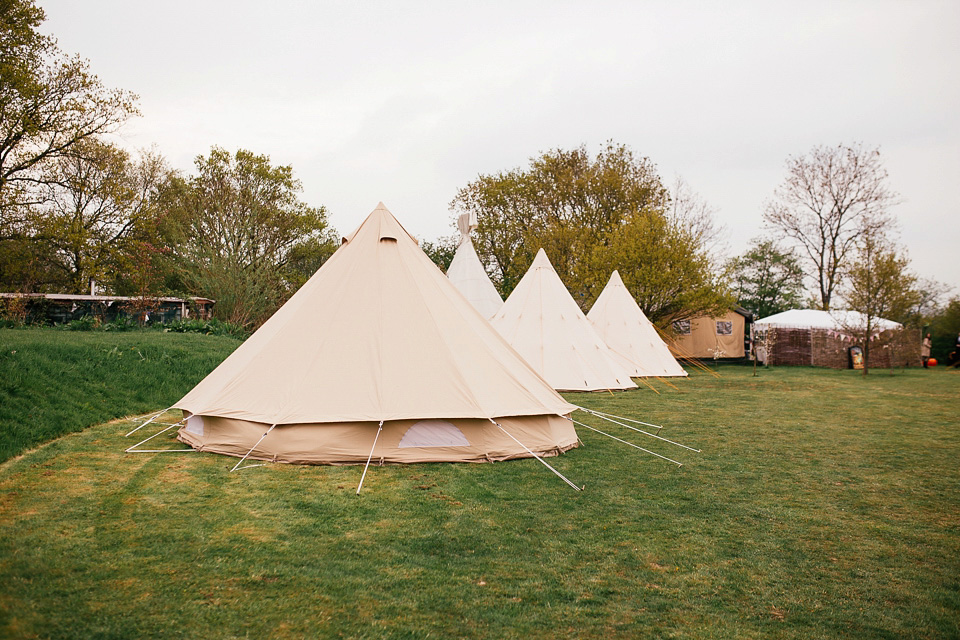 The bride wears a Sabina Motasem gown for her rustic, festival style wedding with glamping near the forrest. Photography by Joanna Nicole.