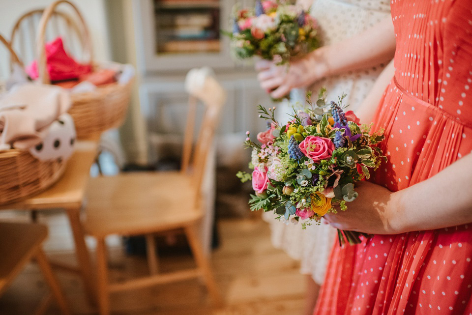 The bride wears a customised Alice & Olivia dress and 1950s wax flower headpiece for her Springtime village hall wedding. Photography by Ellie Gillard.