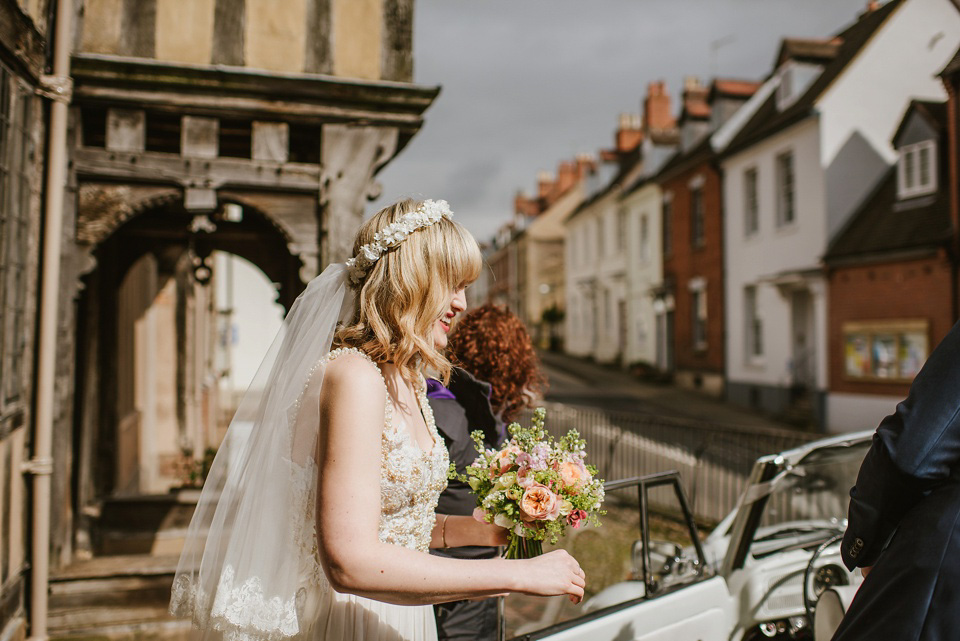 The bride wears a customised Alice & Olivia dress and 1950s wax flower headpiece for her Springtime village hall wedding. Photography by Ellie Gillard.