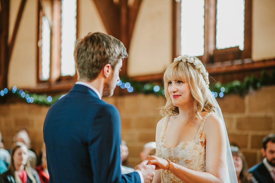 The bride wears a customised Alice & Olivia dress and 1950s wax flower headpiece for her Springtime village hall wedding. Photography by Ellie Gillard.