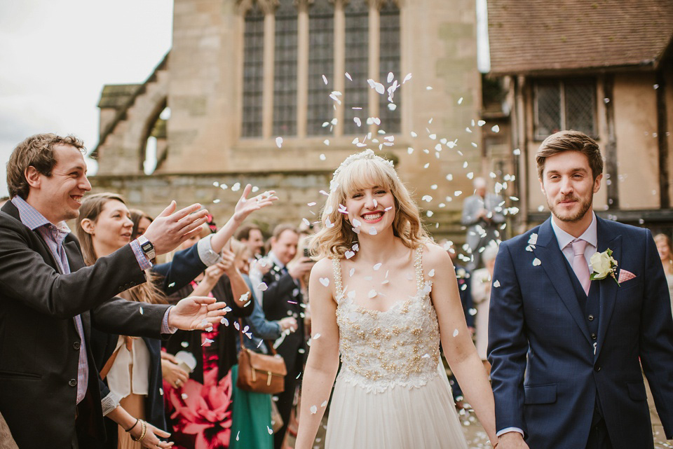 The bride wears a customised Alice & Olivia dress and 1950s wax flower headpiece for her Springtime village hall wedding. Photography by Ellie Gillard.