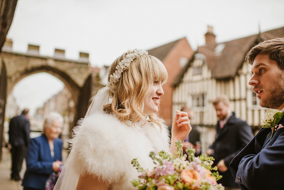 The bride wears a customised Alice & Olivia dress and 1950s wax flower headpiece for her Springtime village hall wedding. Photography by Ellie Gillard.