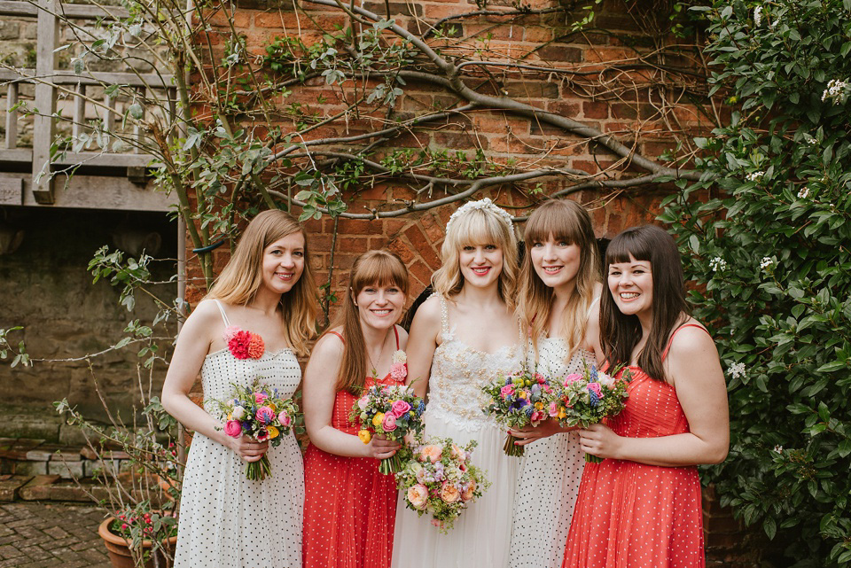 The bride wears a customised Alice & Olivia dress and 1950s wax flower headpiece for her Springtime village hall wedding. Photography by Ellie Gillard.