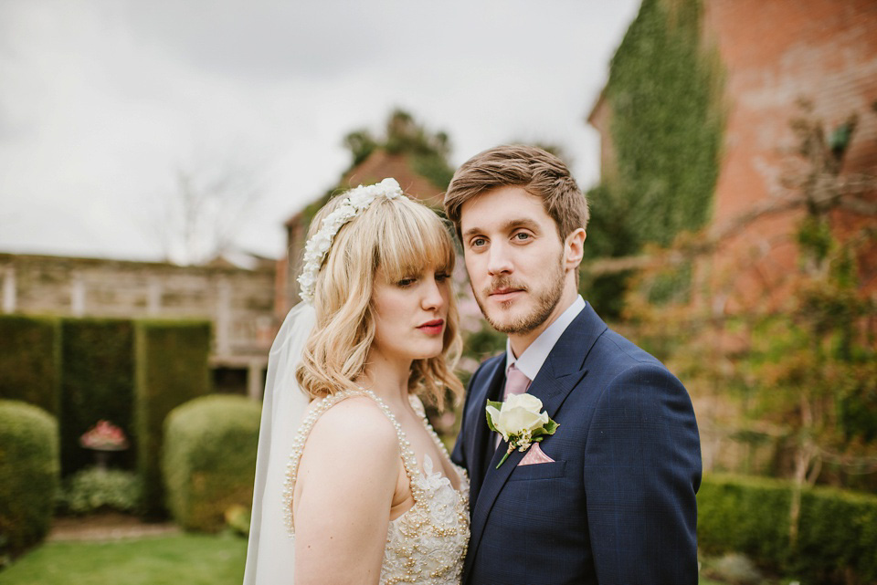 The bride wears a customised Alice & Olivia dress and 1950s wax flower headpiece for her Springtime village hall wedding. Photography by Ellie Gillard.