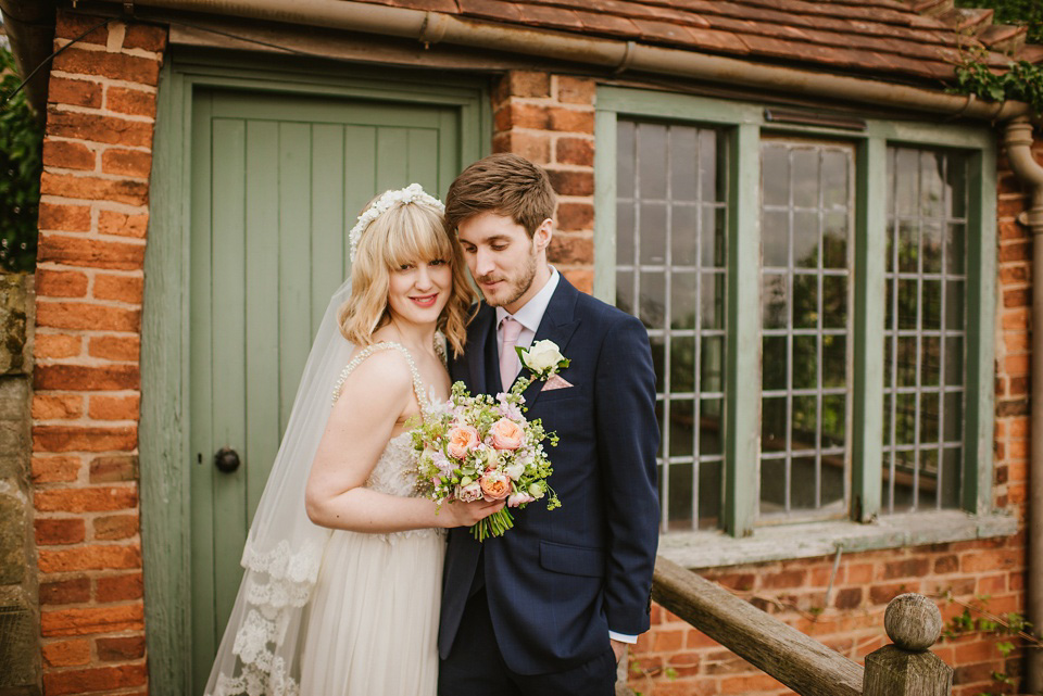 The bride wears a customised Alice & Olivia dress and 1950s wax flower headpiece for her Springtime village hall wedding. Photography by Ellie Gillard.