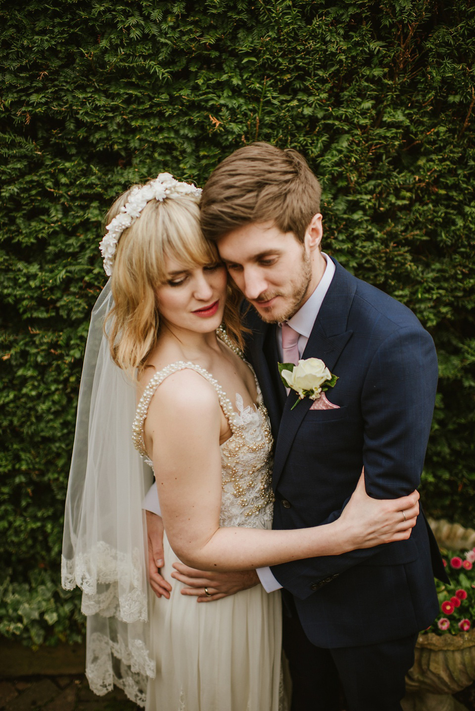 The bride wears a customised Alice & Olivia dress and 1950s wax flower headpiece for her Springtime village hall wedding. Photography by Ellie Gillard.