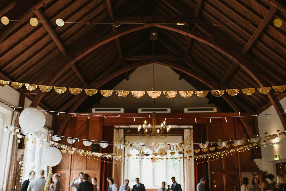 The bride wears a customised Alice & Olivia dress and 1950s wax flower headpiece for her Springtime village hall wedding. Photography by Ellie Gillard.