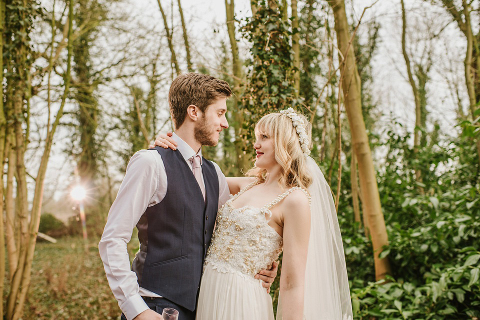 The bride wears a customised Alice & Olivia dress and 1950s wax flower headpiece for her Springtime village hall wedding. Photography by Ellie Gillard.