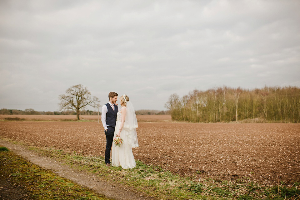 The bride wears a customised Alice & Olivia dress and 1950s wax flower headpiece for her Springtime village hall wedding. Photography by Ellie Gillard.