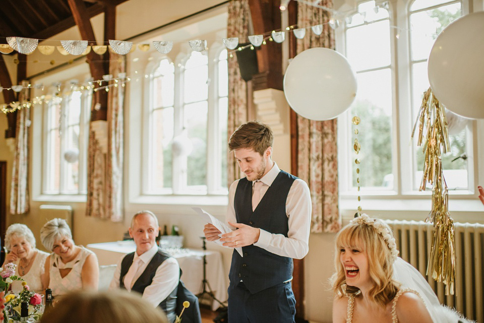 The bride wears a customised Alice & Olivia dress and 1950s wax flower headpiece for her Springtime village hall wedding. Photography by Ellie Gillard.