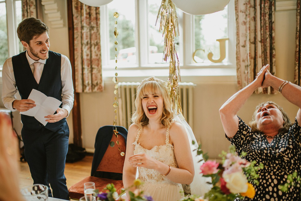 The bride wears a customised Alice & Olivia dress and 1950s wax flower headpiece for her Springtime village hall wedding. Photography by Ellie Gillard.