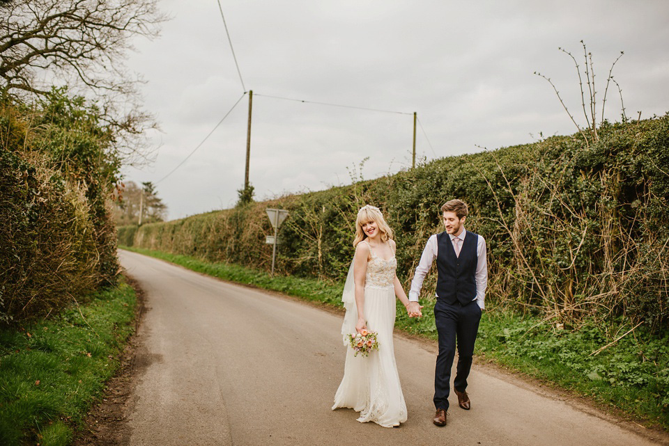 The bride wears a customised Alice & Olivia dress and 1950s wax flower headpiece for her Springtime village hall wedding. Photography by Ellie Gillard.