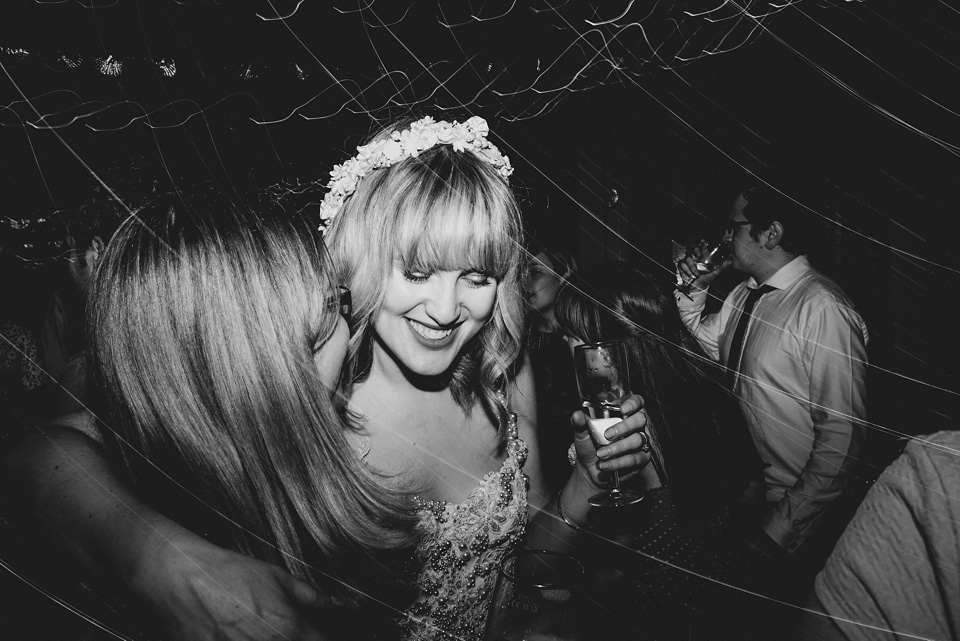 The bride wears a customised Alice & Olivia dress and 1950s wax flower headpiece for her Springtime village hall wedding. Photography by Ellie Gillard.