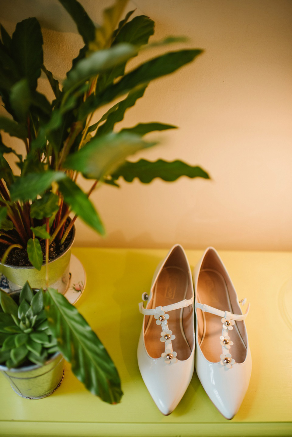 The bride wears a customised Alice & Olivia dress and 1950s wax flower headpiece for her Springtime village hall wedding. Photography by Ellie Gillard.