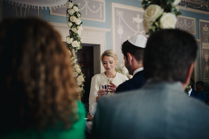 Bride Jess wears an original 1970's vintage Ossie Clarke dress for her Jewish wedding ceremony at Home House in London. Photography by Rebecca Goddard.