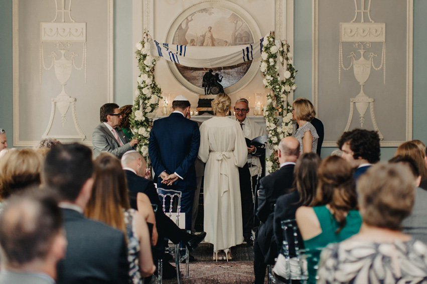 Bride Jess wears an original 1970's vintage Ossie Clarke dress for her Jewish wedding ceremony at Home House in London. Photography by Rebecca Goddard.