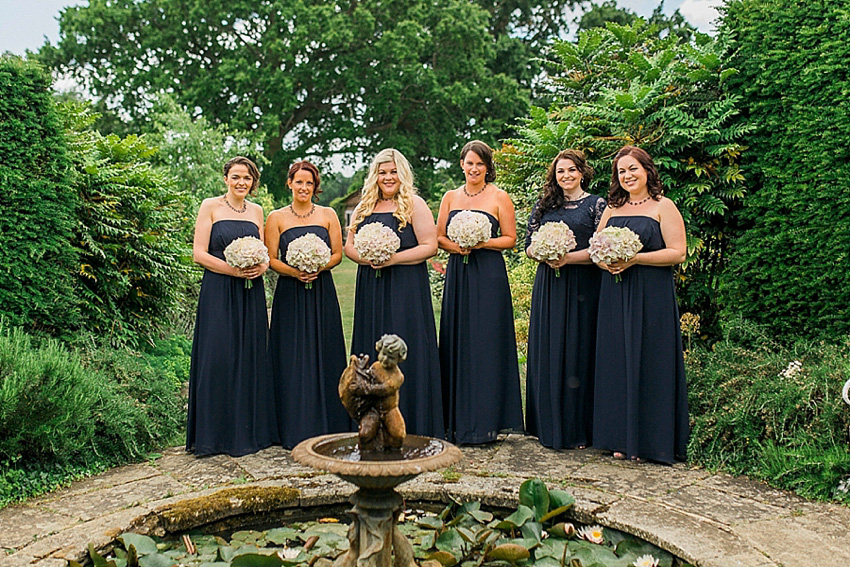 The bride wore a Watters wedding dress for her wedding at The Great Barn at Micklefield Hall in Hertfordshire. The bridesmaids wore navy blue. Photography by Benjamin Stuart.