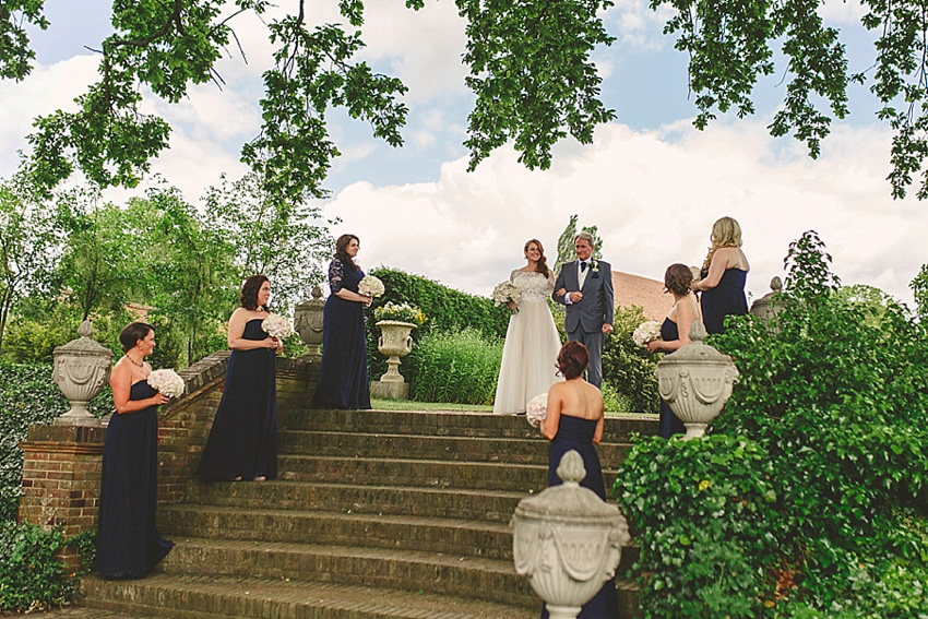 The bride wore a Watters wedding dress for her wedding at The Great Barn at Micklefield Hall in Hertfordshire. The bridesmaids wore navy blue. Photography by Benjamin Stuart.