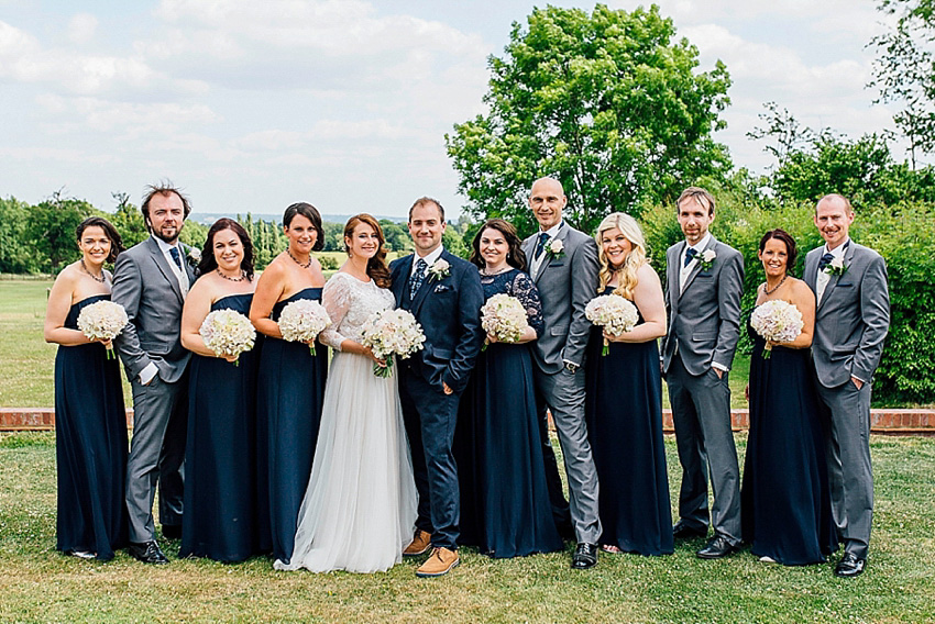 The bride wore a Watters wedding dress for her wedding at The Great Barn at Micklefield Hall in Hertfordshire. The bridesmaids wore navy blue. Photography by Benjamin Stuart.