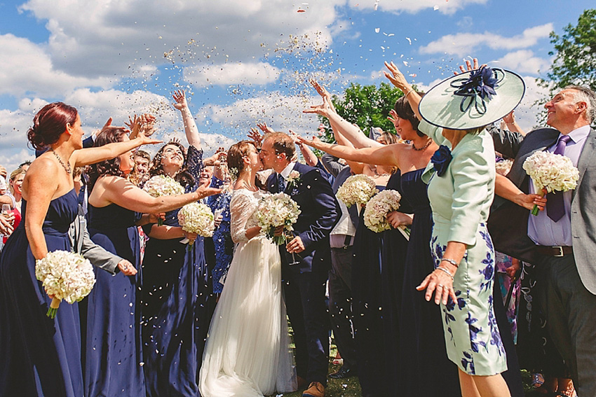 The bride wore a Watters wedding dress for her wedding at The Great Barn at Micklefield Hall in Hertfordshire. The bridesmaids wore navy blue. Photography by Benjamin Stuart.