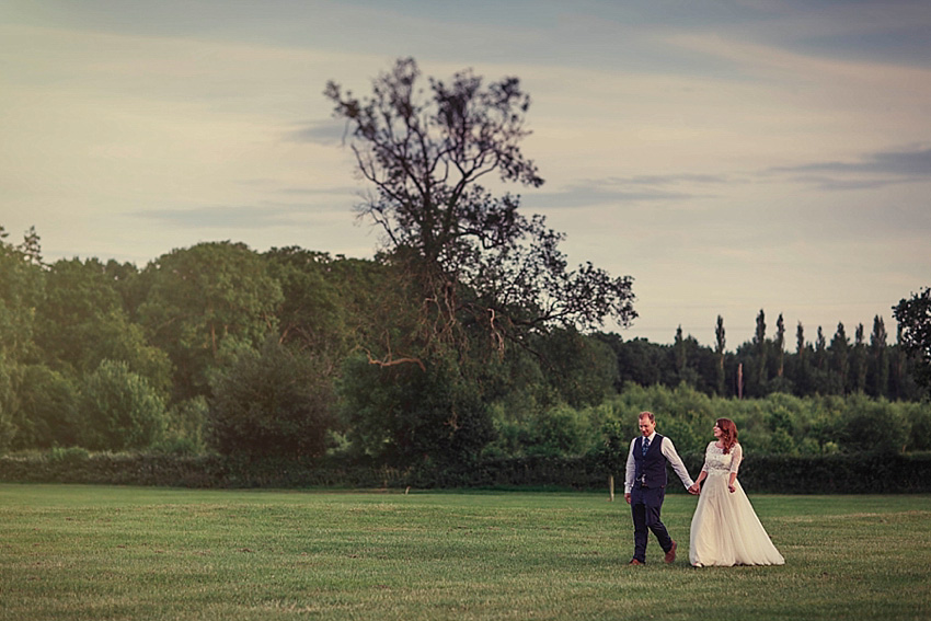 The bride wore a Watters wedding dress for her wedding at The Great Barn at Micklefield Hall in Hertfordshire. The bridesmaids wore navy blue. Photography by Benjamin Stuart.