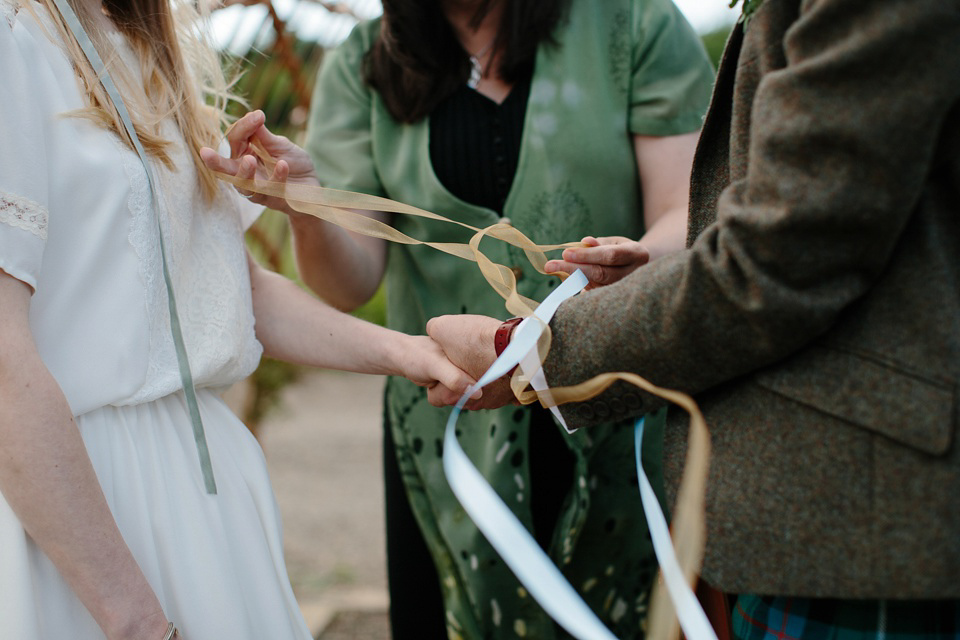 A Humanist handfasting outdoor ceremony at The Secret Herb Garden, just outside Edinburgh. The bride wore 'Minna'. Photography by Caro Weiss.