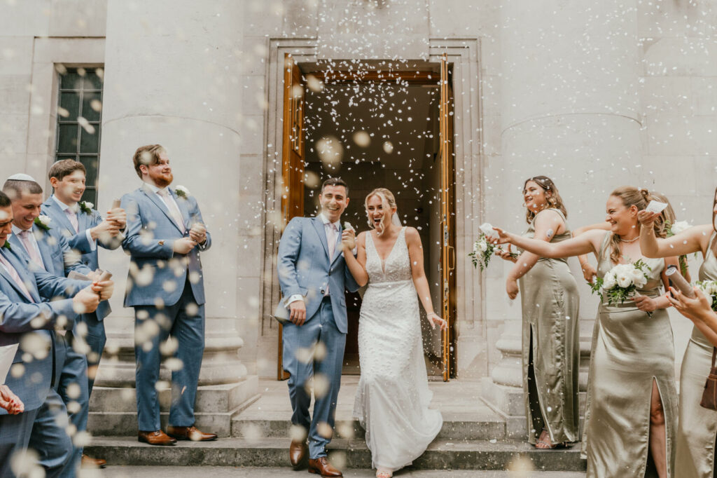 Bride & groom leaving the registry office and being covered in confetti. Shelby Ellis, Kent UK and destination wedding photographer