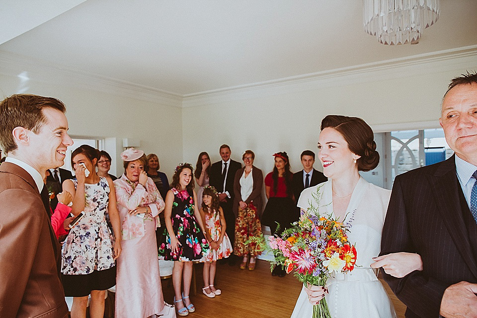 The bride wears a 1950's inspired belted gown by Loulou bridal for her vintage style wedding in North Yorkshire. Photography by Ryan of Shutter Go Click.