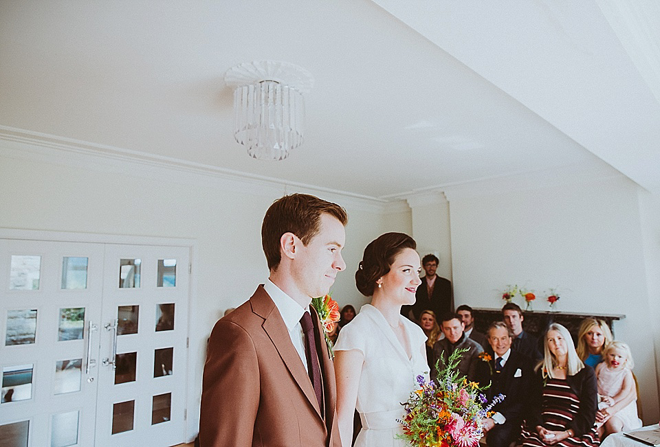 The bride wears a 1950's inspired belted gown by Loulou bridal for her vintage style wedding in North Yorkshire. Photography by Ryan of Shutter Go Click.