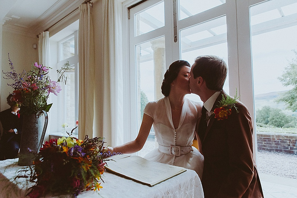 The bride wears a 1950's inspired belted gown by Loulou bridal for her vintage style wedding in North Yorkshire. Photography by Ryan of Shutter Go Click.