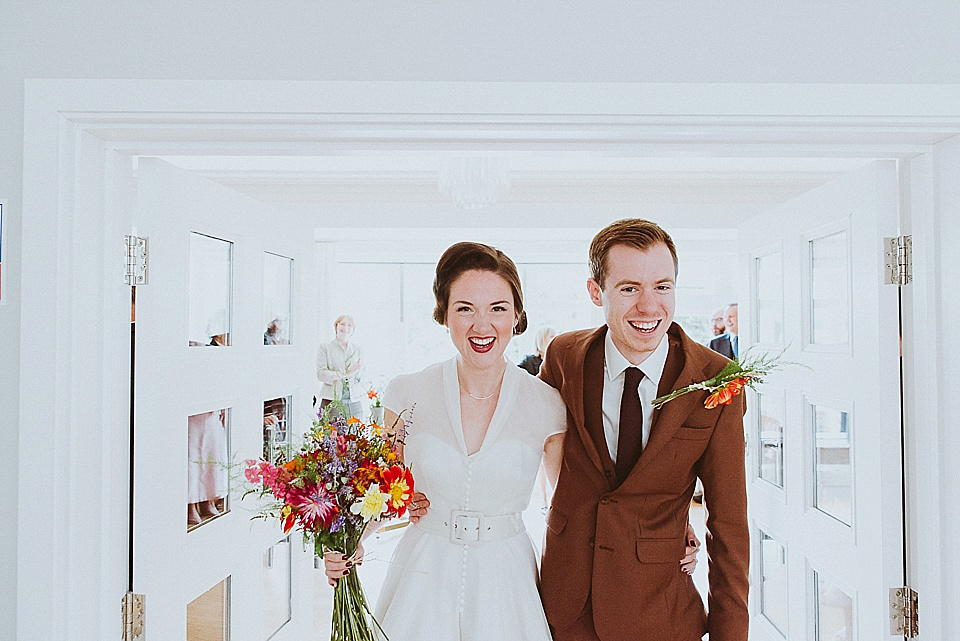 The bride wears a 1950's inspired belted gown by Loulou bridal for her vintage style wedding in North Yorkshire. Photography by Ryan of Shutter Go Click.