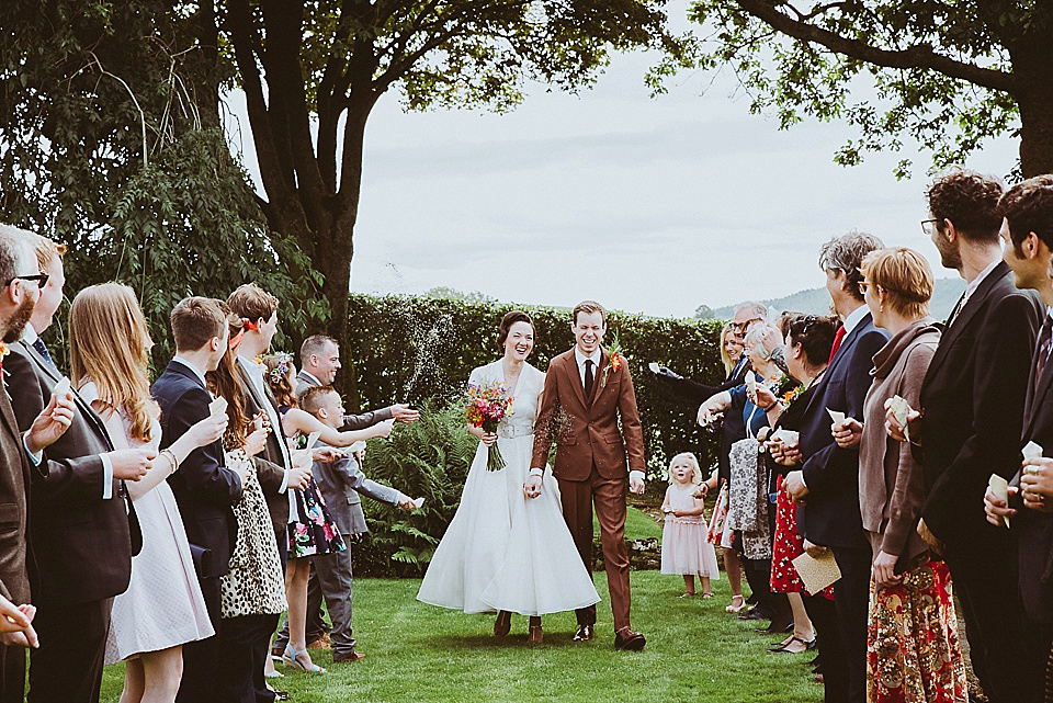 The bride wears a 1950's inspired belted gown by Loulou bridal for her vintage style wedding in North Yorkshire. Photography by Ryan of Shutter Go Click.