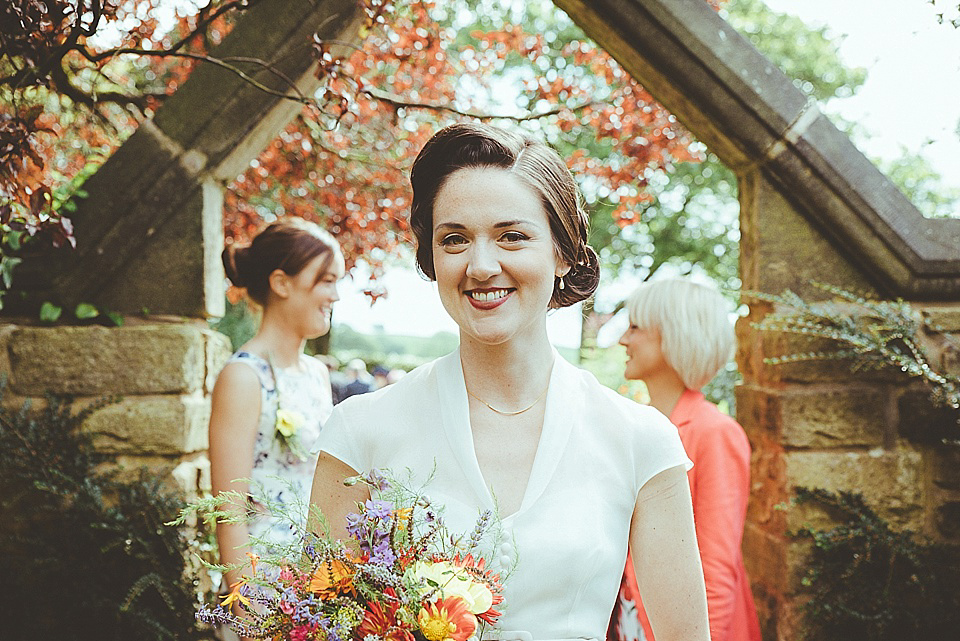 The bride wears a 1950's inspired belted gown by Loulou bridal for her vintage style wedding in North Yorkshire. Photography by Ryan of Shutter Go Click.