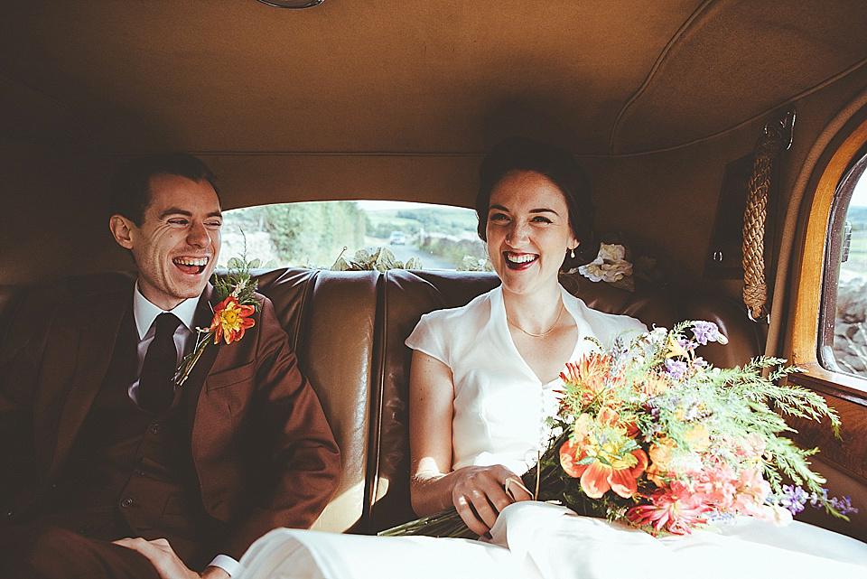 The bride wears a 1950's inspired belted gown by Loulou bridal for her vintage style wedding in North Yorkshire. Photography by Ryan of Shutter Go Click.