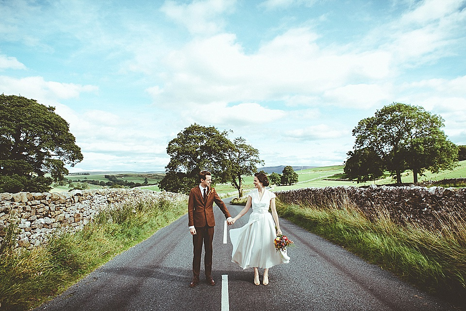 The bride wears a 1950's inspired belted gown by Loulou bridal for her vintage style wedding in North Yorkshire. Photography by Ryan of Shutter Go Click.