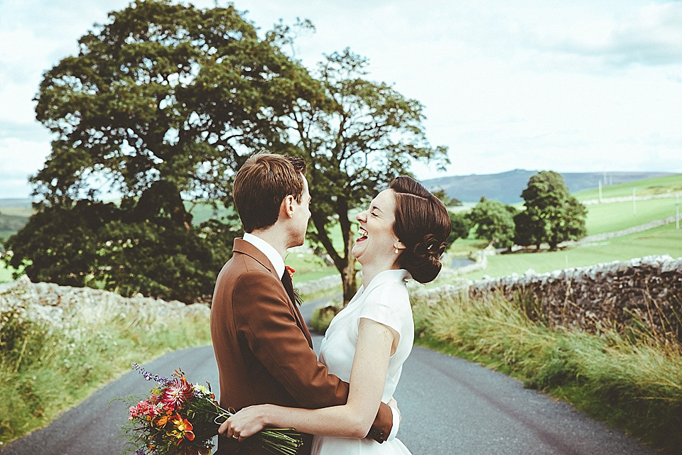 The bride wears a 1950's inspired belted gown by Loulou bridal for her vintage style wedding in North Yorkshire. Photography by Ryan of Shutter Go Click.