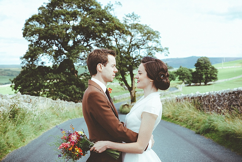 The bride wears a 1950's inspired belted gown by Loulou bridal for her vintage style wedding in North Yorkshire. Photography by Ryan of Shutter Go Click.