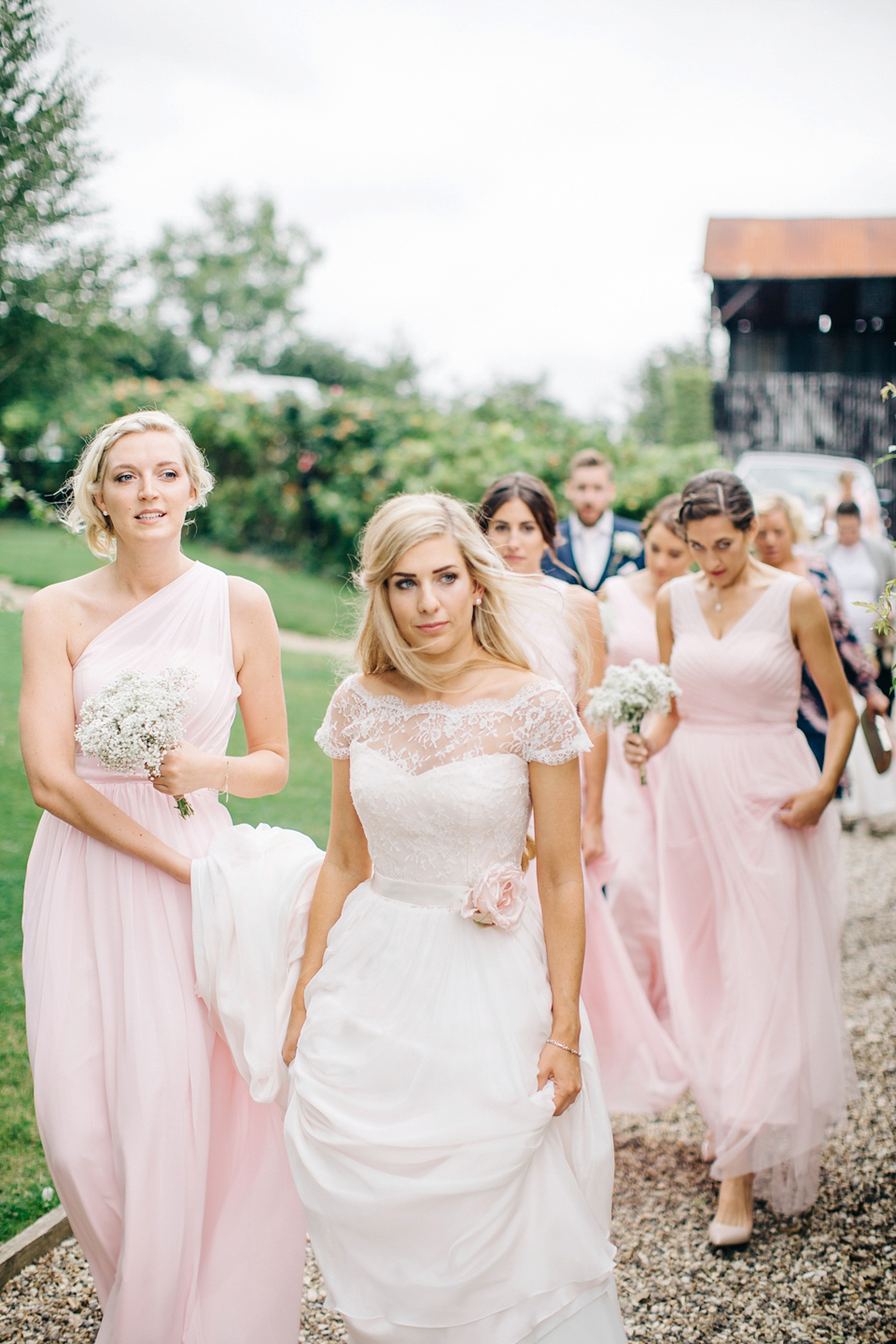 Bride Melanie wears the 'fleur' gown by Naomi Neoh for her Cripps Barn wedding. Her bridesmaids are most pretty in soft pink by 'For Her & For Him'. Images by M&J Photography.