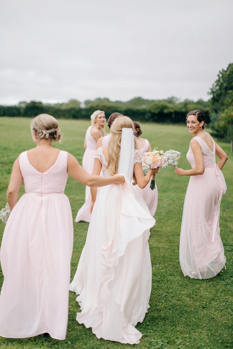 Bride Melanie wears the 'fleur' gown by Naomi Neoh for her Cripps Barn wedding. Her bridesmaids are most pretty in soft pink by 'For Her & For Him'. Images by M&J Photography.