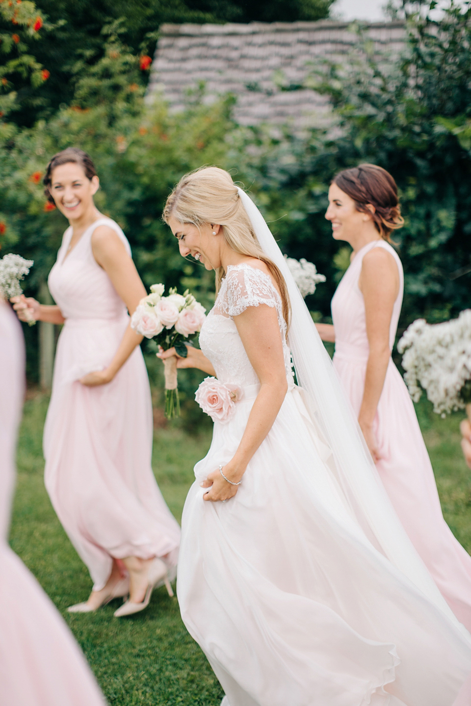 Bride Melanie wears the 'fleur' gown by Naomi Neoh for her Cripps Barn wedding. Her bridesmaids are most pretty in soft pink by 'For Her & For Him'. Images by M&J Photography.