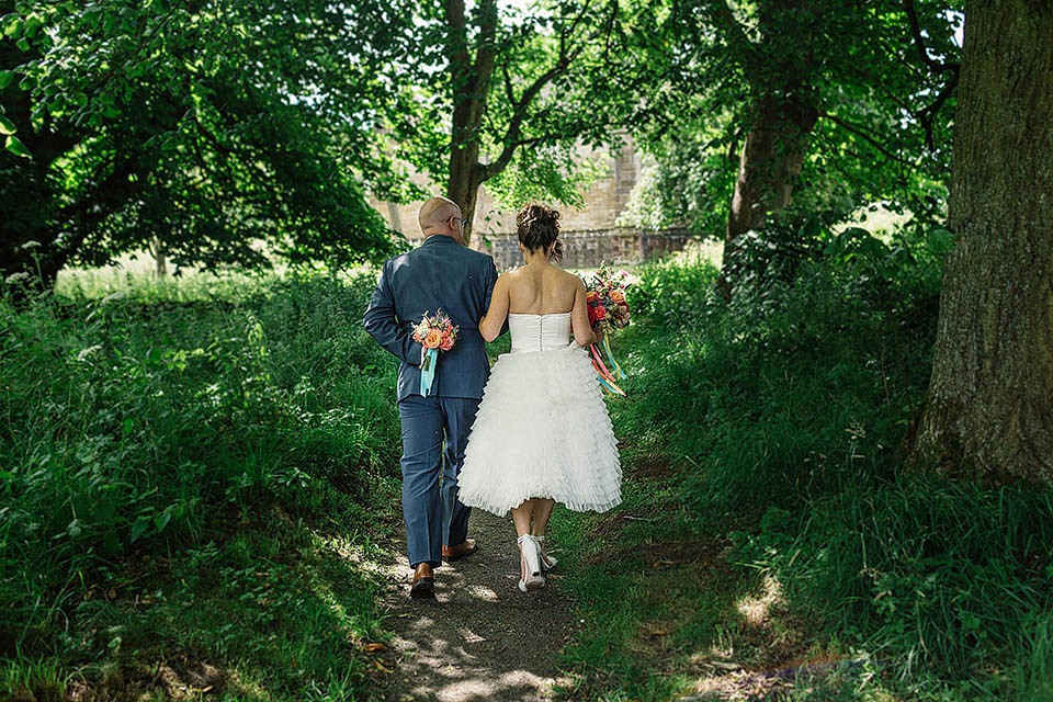 Audrey wore a 1950's inspired tiered wedding dress by Mooshki Bridal for her outdoor wedding in Scotland. The colourful and quirky wedding ceremony was held within the ruins of a chapel. Photography by Paul Joseph.