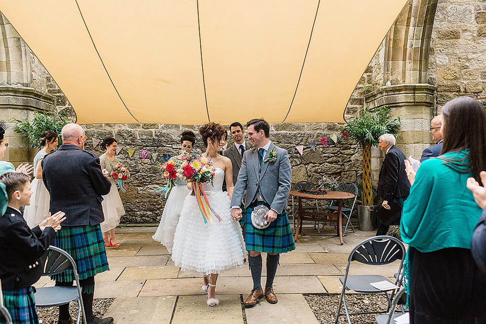 Audrey wore a 1950's inspired tiered wedding dress by Mooshki Bridal for her outdoor wedding in Scotland. The colourful and quirky wedding ceremony was held within the ruins of a chapel. Photography by Paul Joseph.