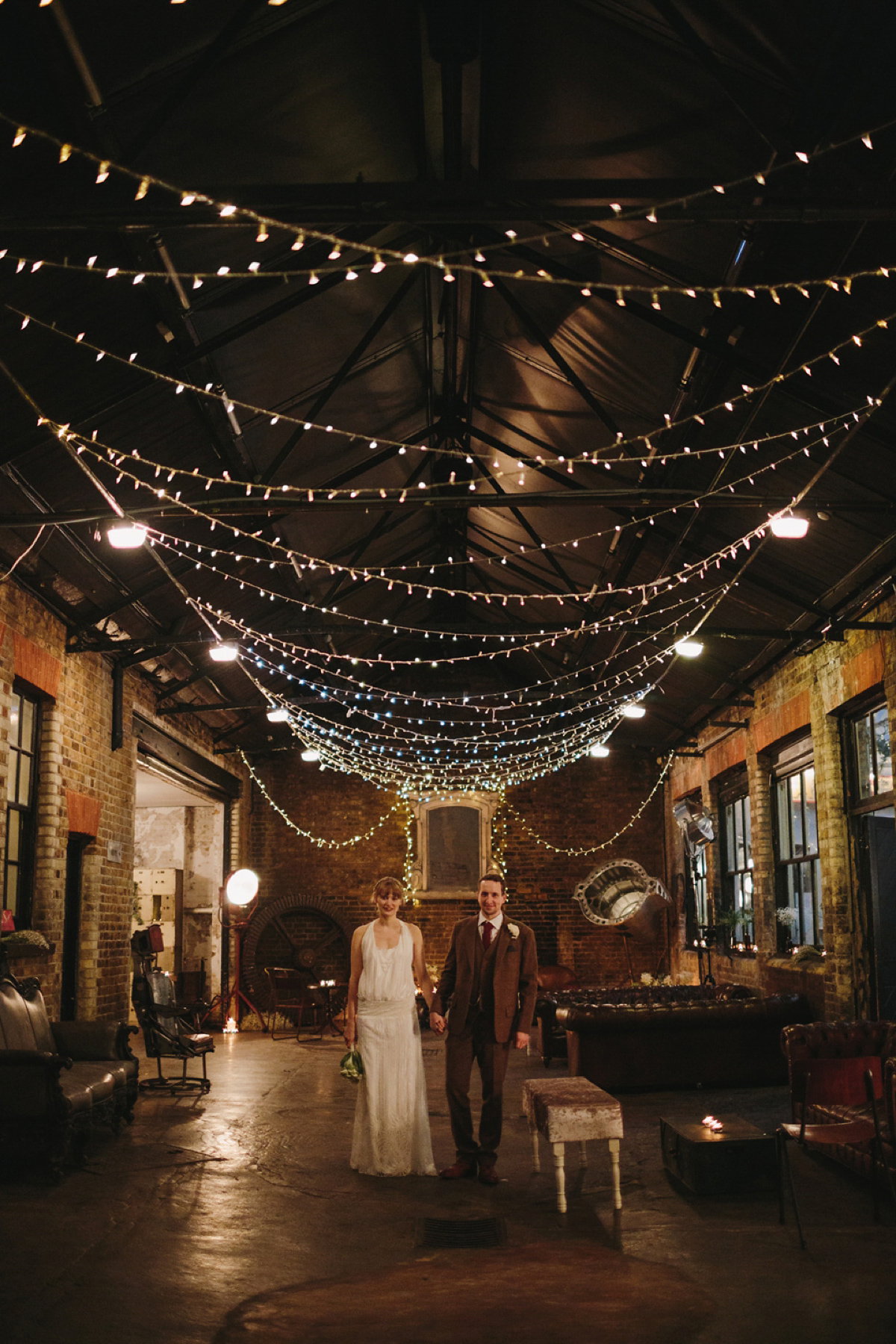 The bride wears a 1920's inspired drop waist gown by Charlie Brear for her cool and quirky wedding at MC Motors in East London. Photography by Emilie White.