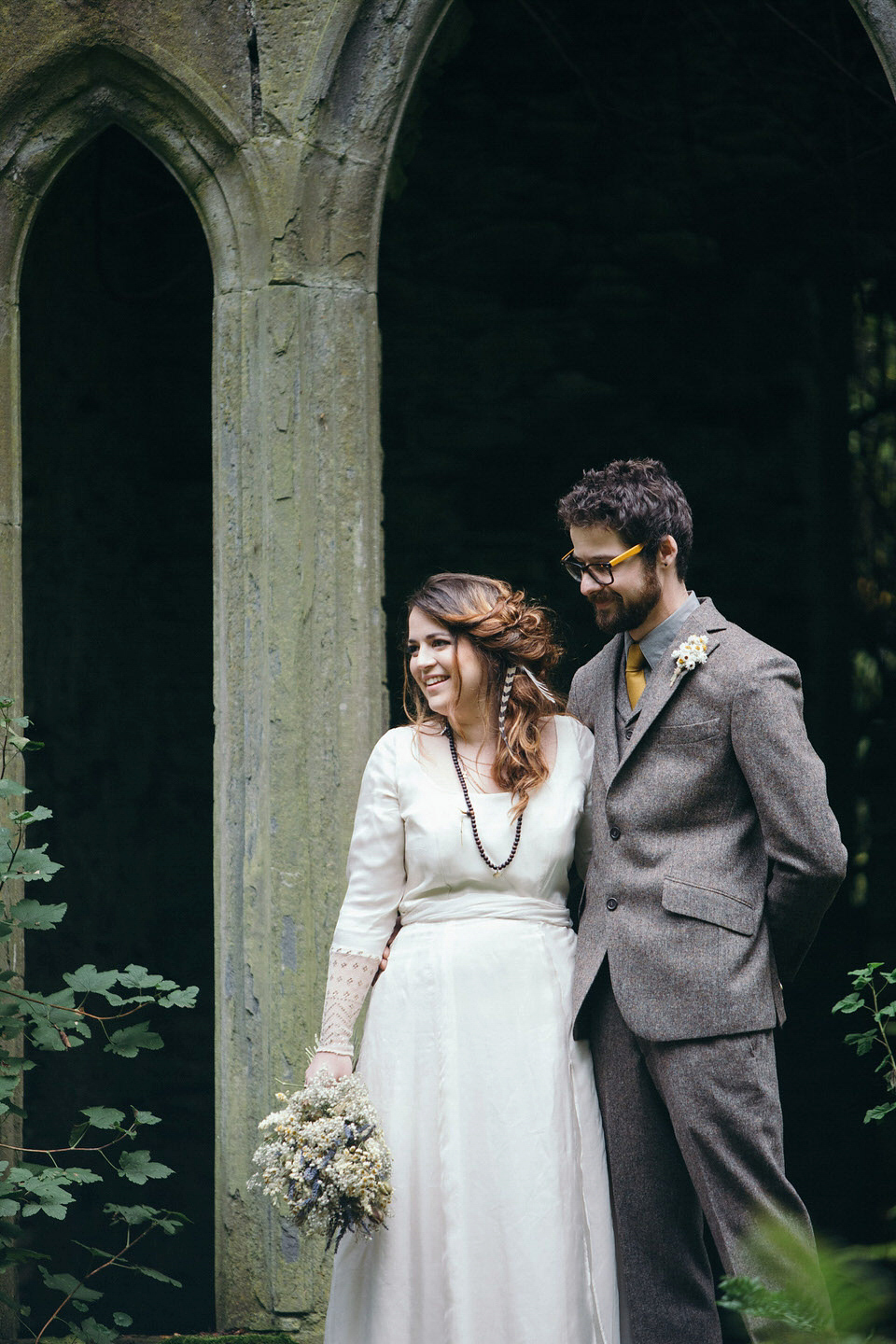 A tweed jacket and feathers in her hair for a boho bride and her eclectic woodland wedding. Images by Mirrorbox Photography.