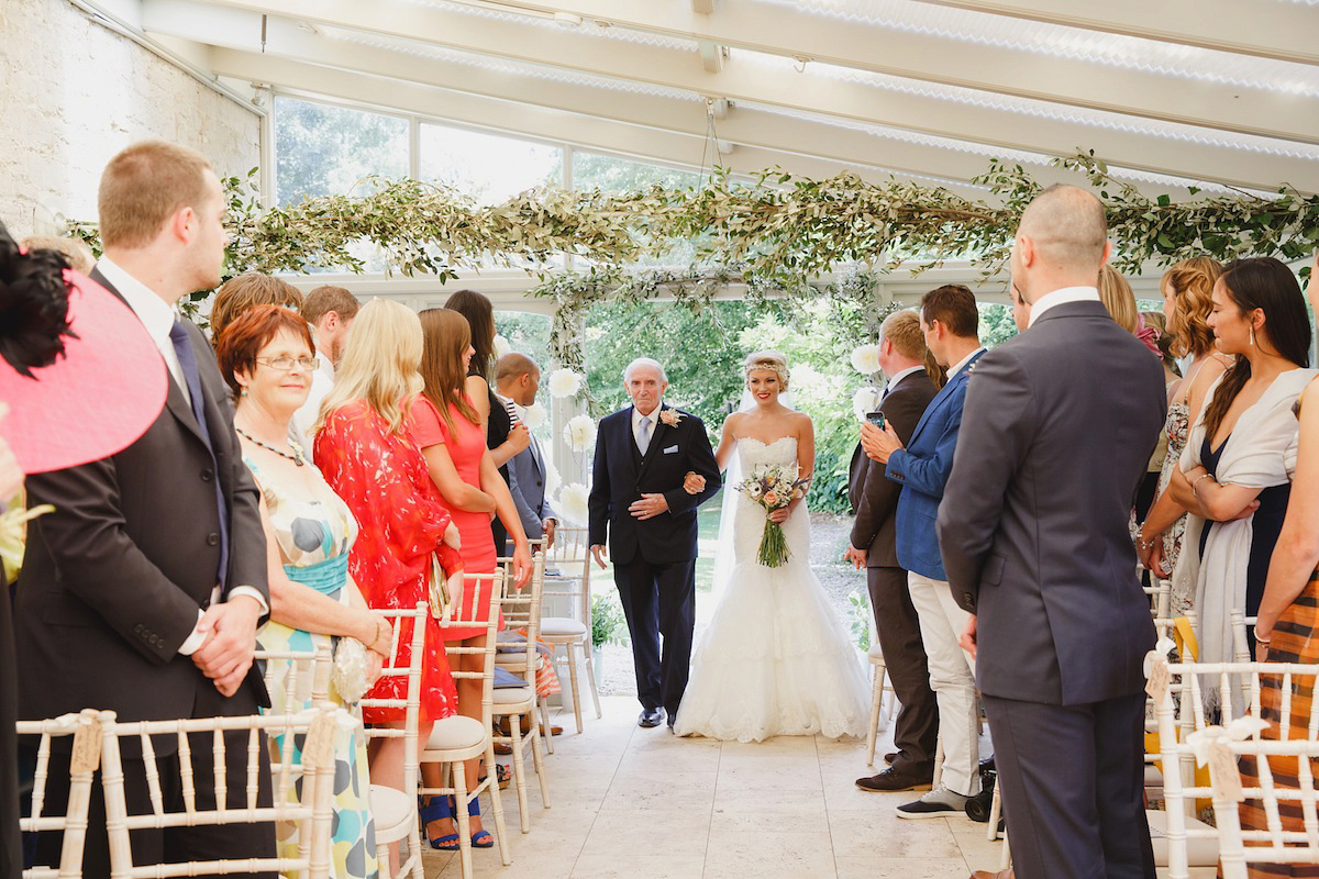 Victoria wears a Pronovias gown with a cathedral length veil for her relaxed, fun and colourful English country garden wedding in the Cotswolds. Photography by Sarah Ann Wright.