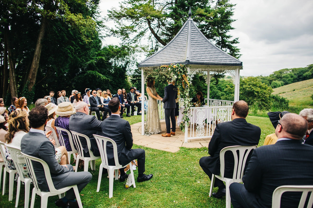 Boho bride Alice wore a pale green lace wedding dress and floral crown for her wild woodland inspired, free spirited South Devon wedding at Langdon Court. Photography by Richard Skins.