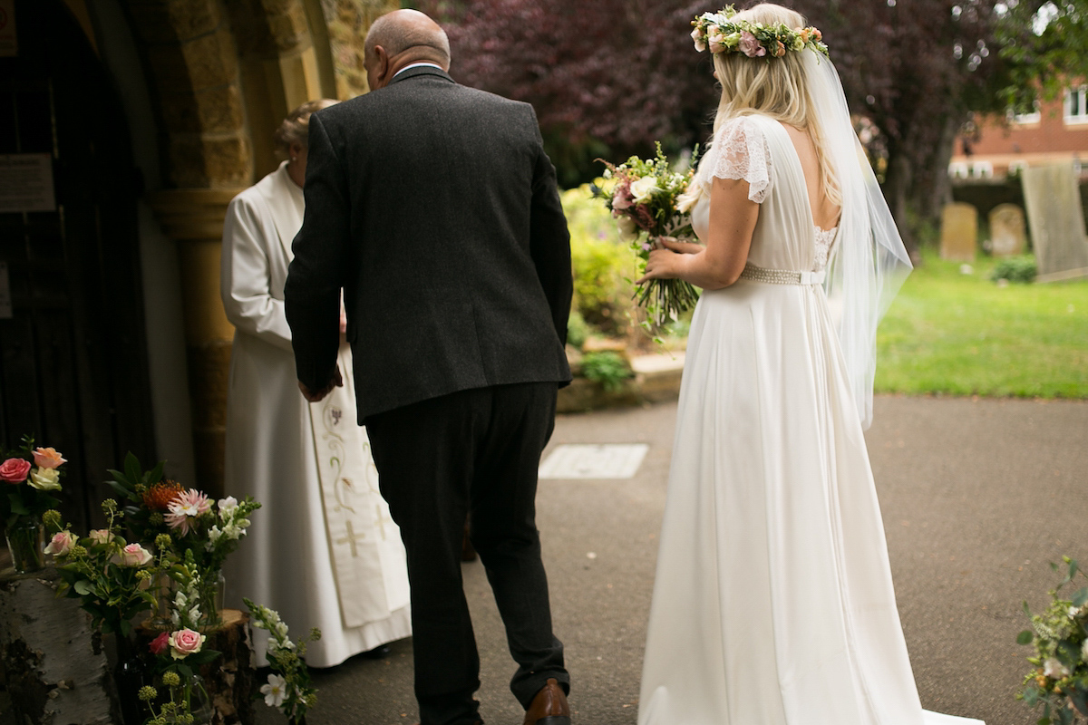 Bride Laura wore a Charlie Brear gown and floral crown for her charming Autumn village hall wedding. Photography by Henry Britten.